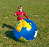 Kind mit Globus auf der Wiese
